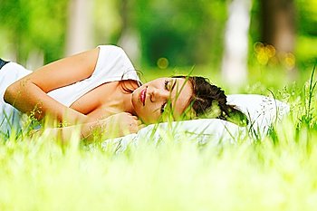 Young woman sleeping on soft pillow in fresh spring grass
