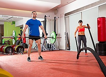 Crossfit fitness gym weight lifting bar man and woman battling ropes workout