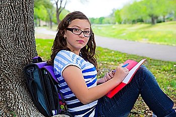 Clever student teenager girl with school bag resting relaxed under park tree