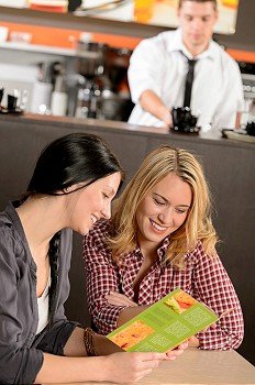 Two young female customers reading menu in pub
