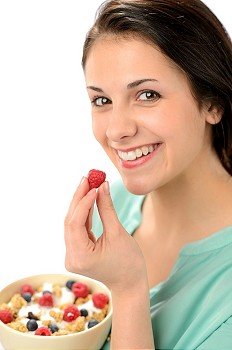 Happy woman with a bowl of healthy cereal and fruits