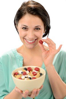 Friendly girl posing with cereal bowl and berries