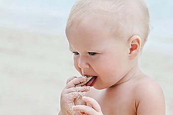 Baby eating sand on the beach