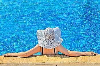Woman with white hat relaxing at the edge pool