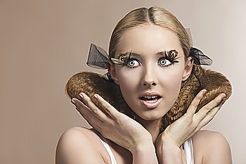 young sensual girl in beauty portrait with surprised expression, blonde creative hair-style and cute feathered make-up