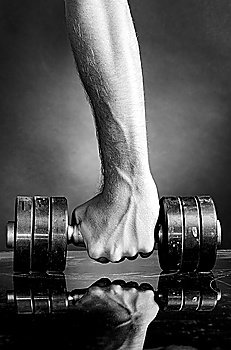 male hand is holding metal barbell on dark gray background