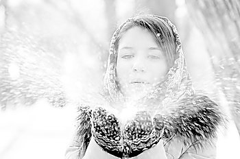 young woman is blowing snow in winter park