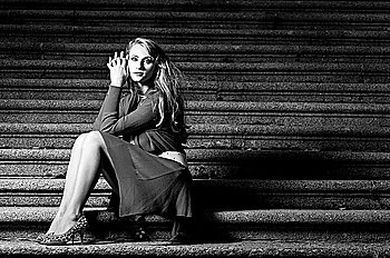fashionable woman is sitting on stairs at evening