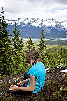 Rear view of a girl sitting with mountain range in the background, Bald Hills Trail, Jasper National Park, Alberta, Canada
