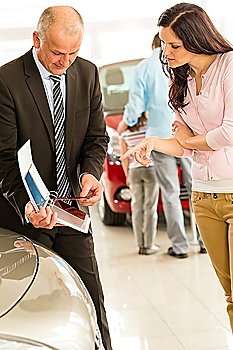 Car salesman showing color swatches to female customer