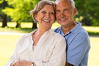 Senior citizen couple laughing at camera outdoors