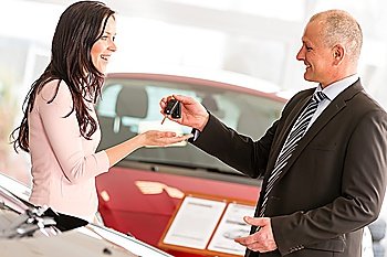 Salesman handing car keys to smiling woman