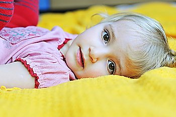 Beautiful little girl  lying on  bed at  house