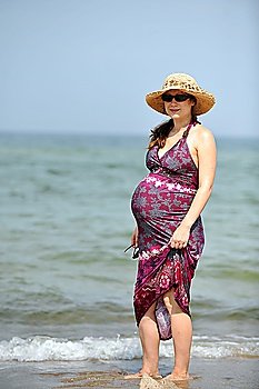 Pregnant young beautiful woman in  hat relaxing at  beach