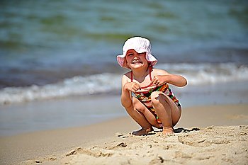 Beautiful little girl in hat relaxing at beach