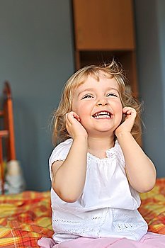 cheerful little girl sits on bed of parents