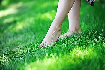 woman´s feet walking barefoot on  grass.  summer´s day