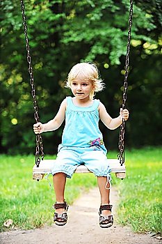 Swinging pretty little girl in park