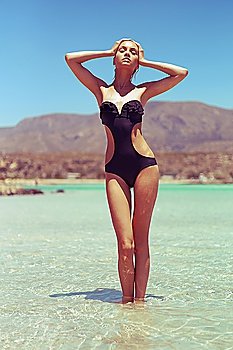 Gorgeous young lady in a black swimsuit at the sea