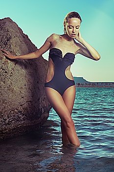 Gorgeous young lady in a black swimsuit at the sea