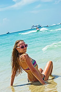 young girl in a bathing suit sitting on the beach