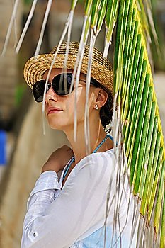 Woman in sunglasses near palm tree wearing hat
