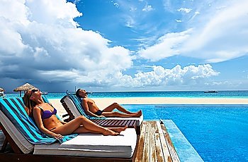 Couple relaxing in chaise lounge at the poolside