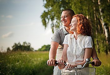 Young couple sitting one bicycle and looking at something