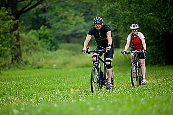happy Man and woman exercising with bicycles outdoors, they are a couple in forest