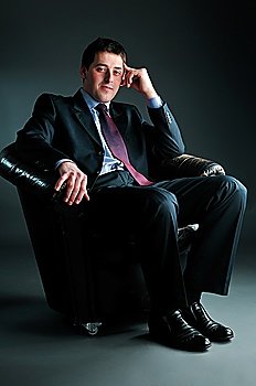 young businessman sitting in black chair, tonned in blue-green tint