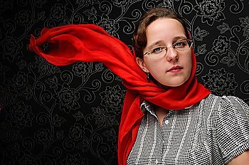 Charming woman over dark background with red shawl on the wind