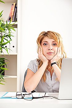 Woman looking surprised with laptop sitting at the table in the office
