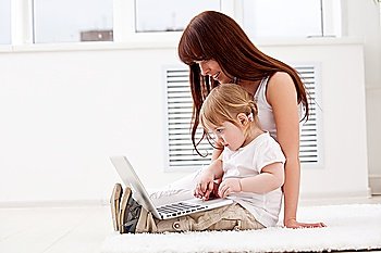Happy young mother and her  daughter using a laptop