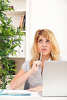 Woman looking surprised with laptop sitting at the table in the office