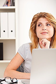 Portrait of beautiful young business woman sitting at desk in the office
