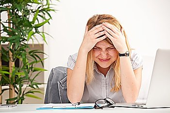 Mature woman with headache sitting at the table in the office