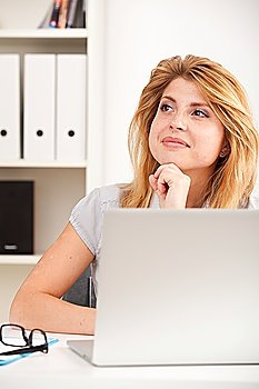 Portrait of beautiful young business woman sitting at desk in the office