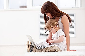Happy young mother and her  daughter using a laptop