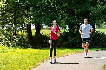 Caucasian boyfriend and girlfriend running a race in sunny park