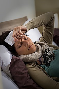 Young ill woman in bed having high fever flu