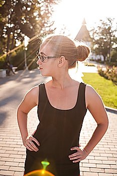 She is Looking away. Young 20s blond haired women posing outdoors weared black tank top in glasses. She is very pretty and fresh looking.