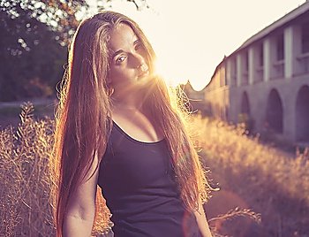 Side view of blonde 20s female girl at sunset, backlit. Deep mysterious look. Pretty young lady outdoors rejoice of warm weather fall