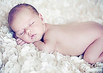 Cute baby sleeping on soft white petals