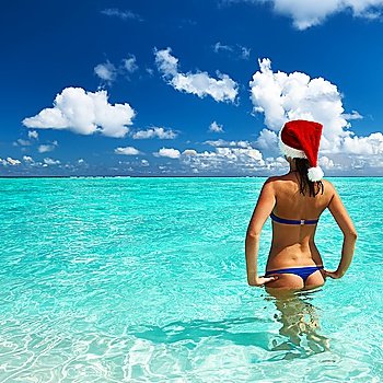 Woman in santa´s hat in bikini at tropical beach