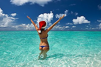 Woman in santa´s hat in bikini at tropical beach