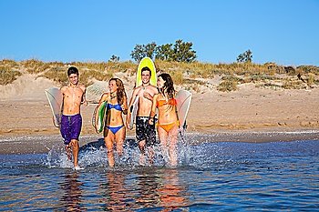 surfer teenagers boys and girls group running happy to the beach splashing water