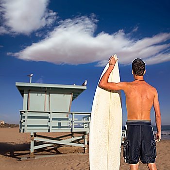 Boy surfer back rear view holding surfboard on santa Monica Lifeguard house California