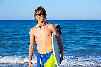 Boy teen surfer happy holing surfboard on the beach shore