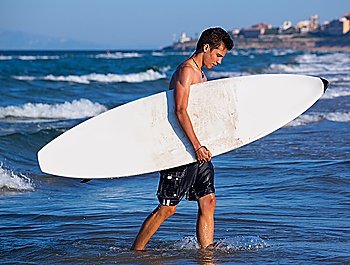 boy handsome surfer holding surfboard coming out from the waves