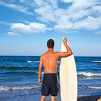 Boy surfer back rear view holding surfboard on blue beach